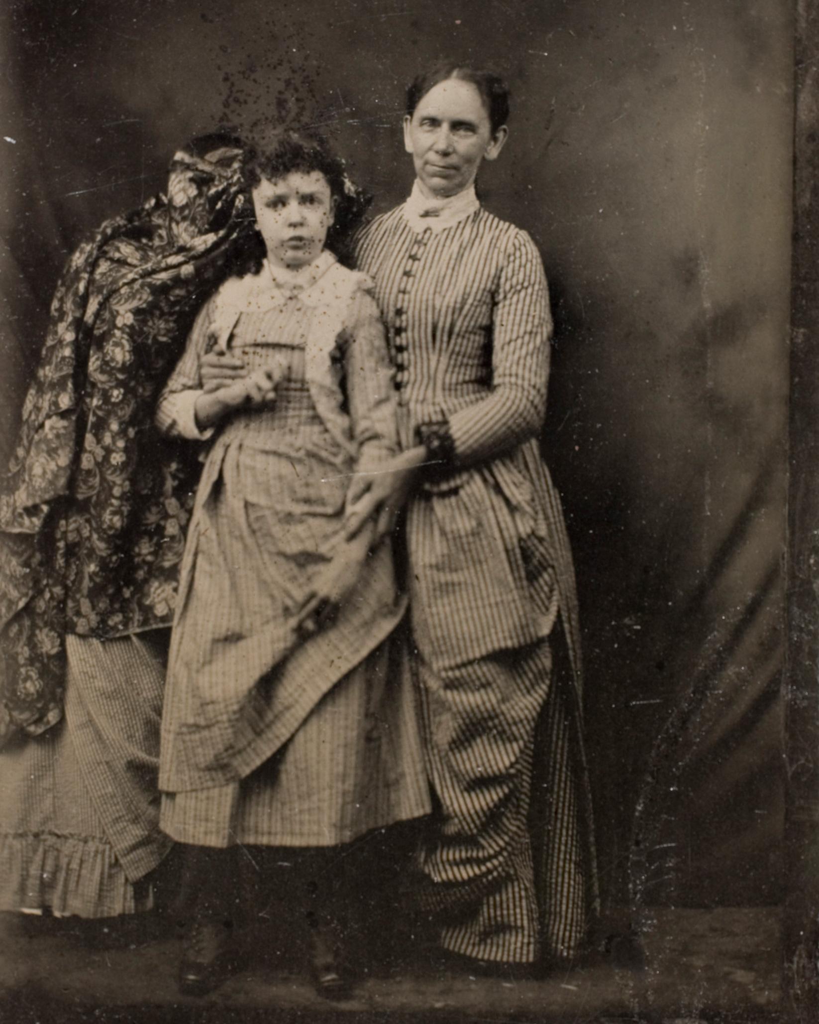 A woman and her daughter posing for the camera. 